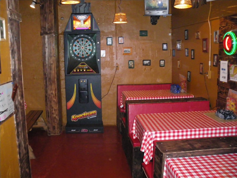 Dart board and tables inside American Pizza Man