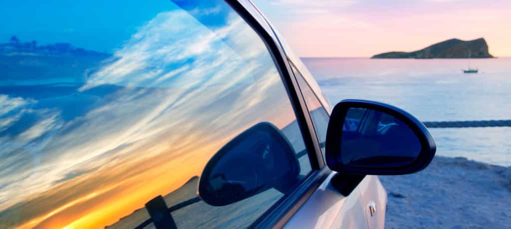 Car Parked on beach with sunset reflection in window