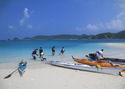 Canoes on Zamami beach with people in water